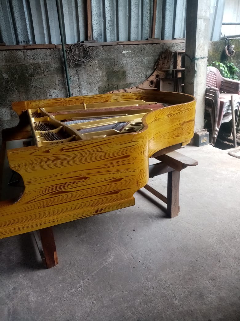 Artisan wood finish on custom grand piano body during assembly at Ranjan Fernando Piano Centre
