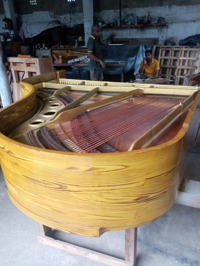 Workshop technicians assembling restrung grand piano soundboard and wooden rim