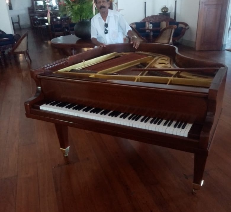 Ranjan Fernando, founder of Ranjan Fernando Piano Centre, beside a restored grand piano in the studio