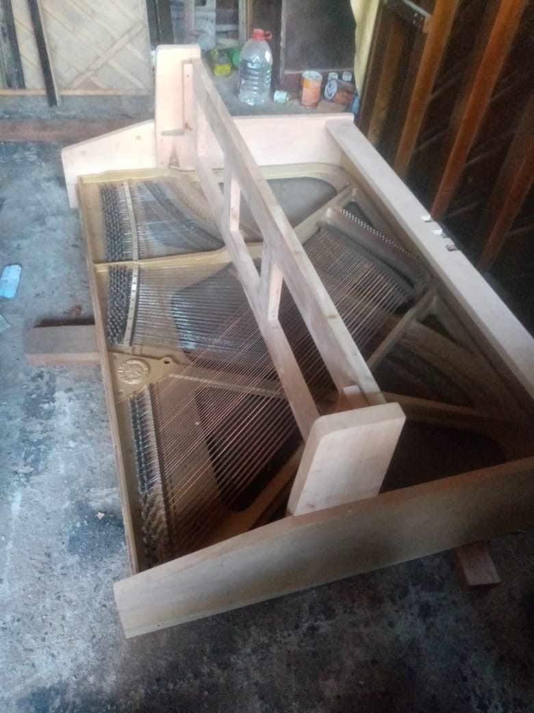 Raw wooden timber back frame and acoustic soundboard of an upright piano under restoration